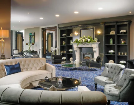 Elegant hotel lounge with plush sofas, fireplace, and decorative flowers, ideal for relaxation.
