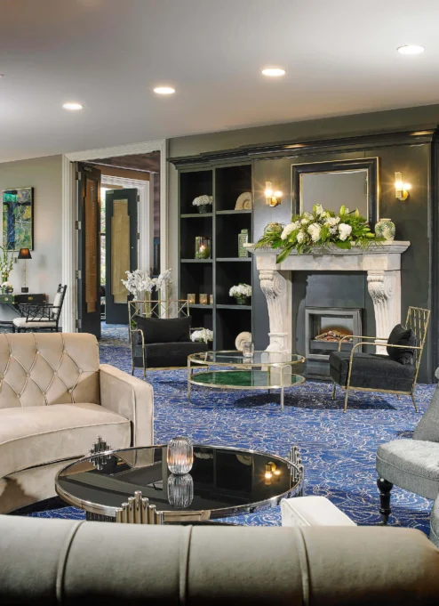 Elegant hotel lounge with plush sofas, fireplace, and decorative flowers, ideal for relaxation.