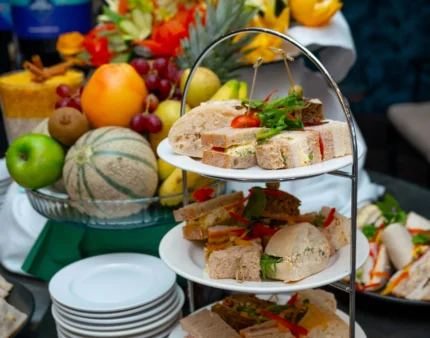 Afternoon tea with assorted sandwiches and fresh fruits in a cosy hotel setting.