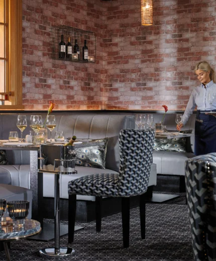 Elegant restaurant setting with a waitress preparing tables, warm lighting, and stylish decor.