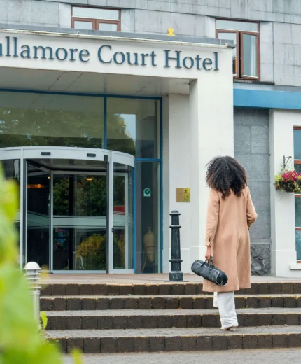 Woman approaching Tullamore Court Hotel entrance on a sunny day.