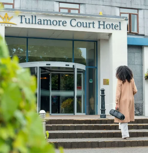 Woman approaching Tullamore Court Hotel entrance on a sunny day.