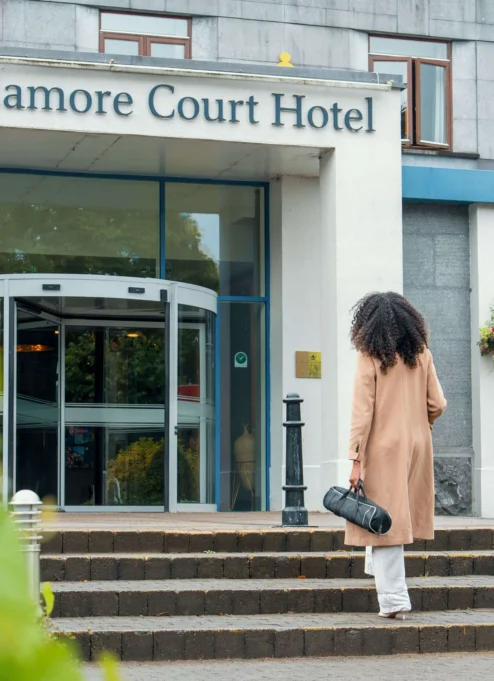 Woman approaching Tullamore Court Hotel entrance on a sunny day.