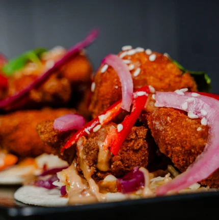 Crispy fried chicken tacos with pickled onions and red peppers.