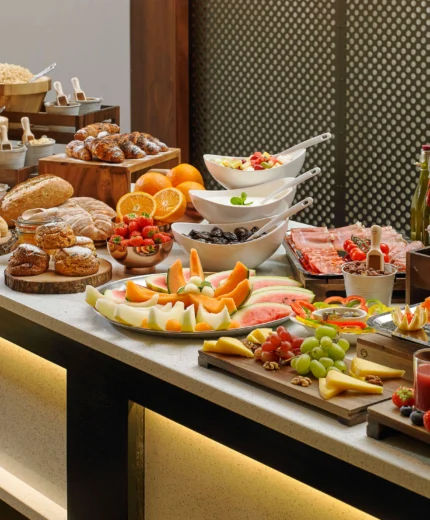 A family enjoying a lavish breakfast buffet with fresh fruits, pastries, and juices.