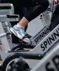 Close-up of people enjoying a spin class at a hotel gym, focusing on legs pedalling.