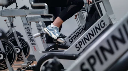 Close-up of people enjoying a spin class at a hotel gym, focusing on legs pedalling.