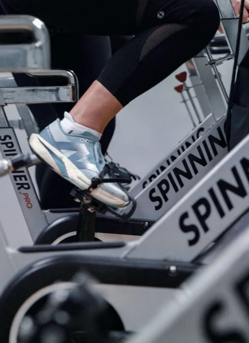 Close-up of people enjoying a spin class at a hotel gym, focusing on legs pedalling.