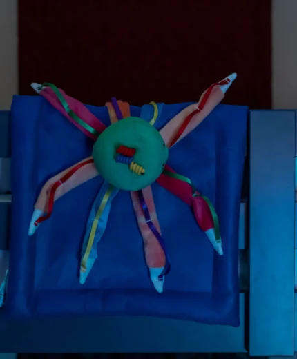 Colourful octopus toy on a blue bed in a cosy hotel room