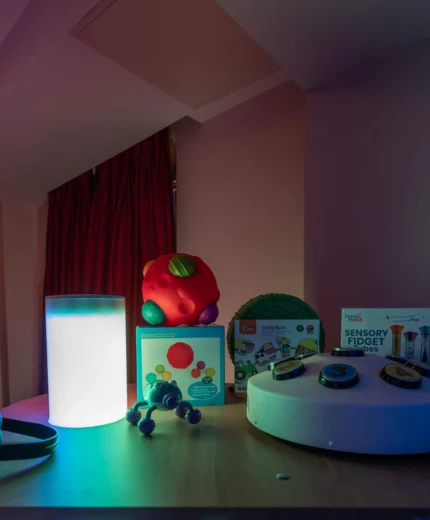 Family-friendly hotel room with sensory toys on a table, illuminated by soft lighting.