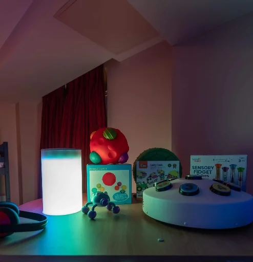 Family-friendly hotel room with sensory toys on a table, illuminated by soft lighting.