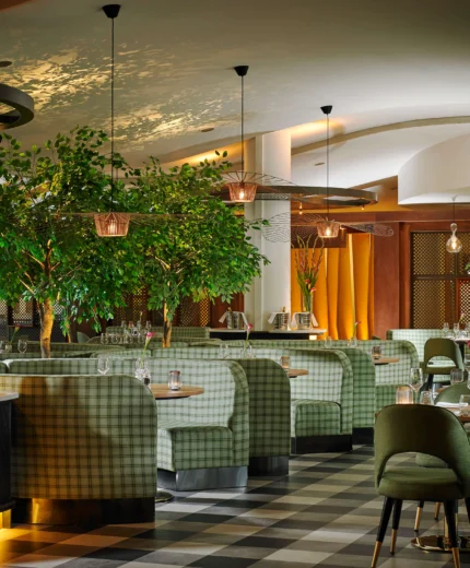 Modern restaurant setting with cosy seating and lush greenery.