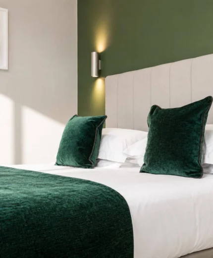 Cosy hotel room with plush green bedding and soft lighting, creating a warm and relaxing ambiance.