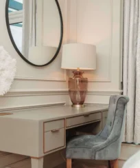 Elegant hotel room with a plush chair by a vanity and warm lighting.