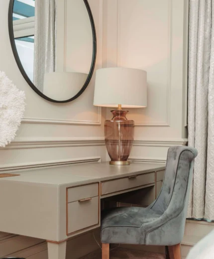 Elegant hotel room with a plush chair by a vanity and warm lighting.