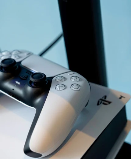 A gaming console and controller on a table in a cosy hotel room setting.
