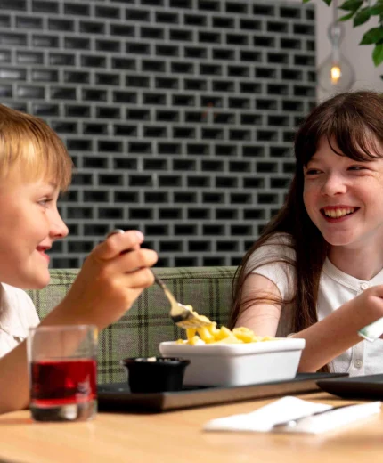 A happy brother and sister enjoy a meal together at a cosy restaurant.
