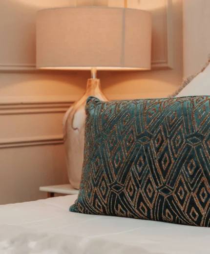 Elegant hotel room with plush pillow and stylish lamp.