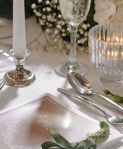 Elegant dining table with floral centrepiece, candlelight, and wedding invitation.