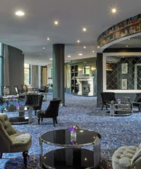 Cosy hotel lounge with comfy seating and bookshelf wallpaper, inviting for families to relax.