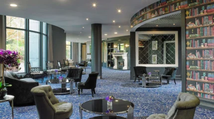 Cosy hotel lounge with comfy seating and bookshelf wallpaper, inviting for families to relax.