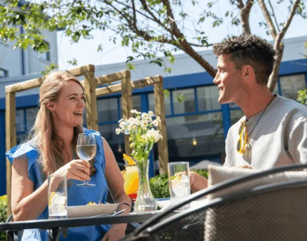 A couple enjoying drinks and food at an outdoor terrace surrounded by greenery at Tullamore Court Hotel.