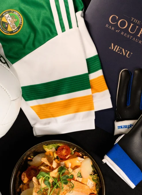Irish sports jersey, football, gloves, and gourmet dish on table.