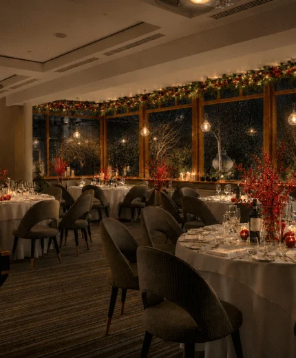 Cosy hotel restaurant with festive décor and elegantly set tables for dining.