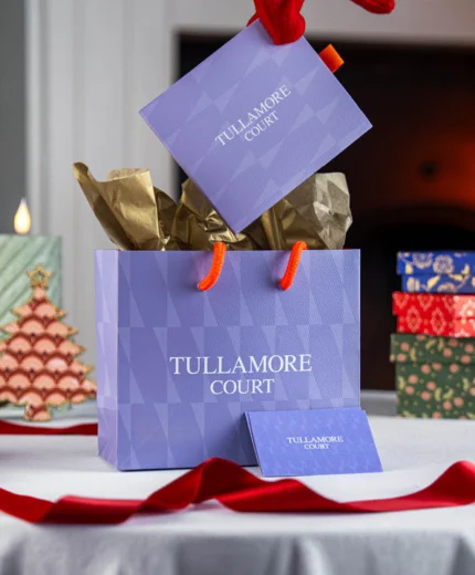 Festive Tullamore Court Hotel gift bag with Christmas decorations on a table.