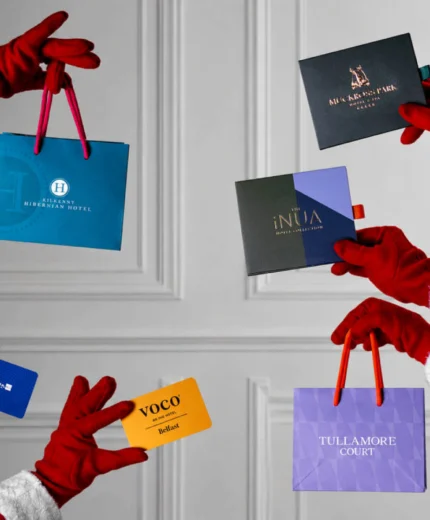Festive hands holding gift cards for Tullamore Court Hotel and more, against a white panelled background.